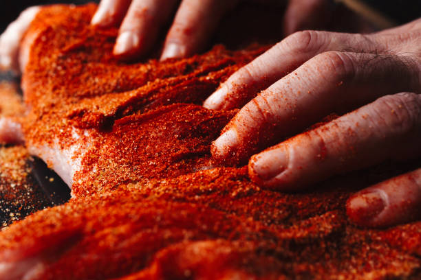 istock Man preparing raw piece of meat, rubbing different spices and herbs in it before roasting 1179800702
