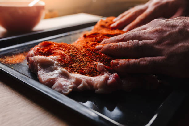 istock Man preparing raw piece of meat, rubbing different spices and herbs in it before roasting 1179800703