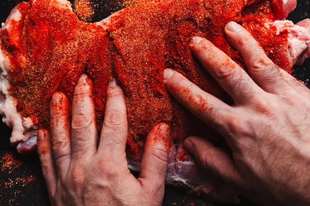 istock Man preparing raw piece of meat, rubbing different spices and herbs in it before roasting 1179800724
