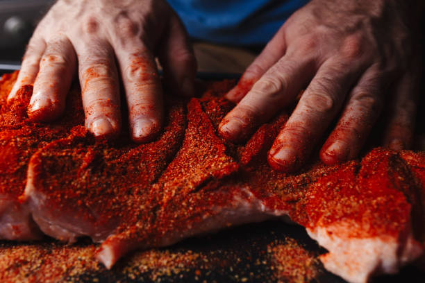 istock Man preparing raw piece of meat, rubbing different spices and herbs in it before roasting 1179800727