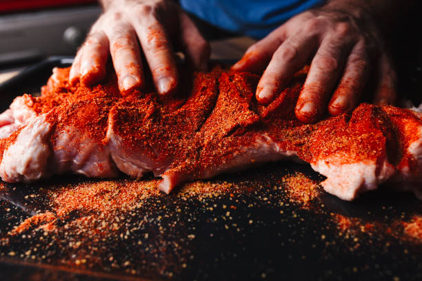 istock Man preparing raw piece of meat, rubbing different spices and herbs in it before roasting 1179800742