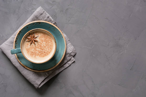 Masala Indian tea or coffee in blue cup with spices and cinnamon on black. Top view. Masala Indian tea or coffee in blue cup with spices and cinnamon on black concrete table. Top view. chai stock pictures, royalty-free photos & images