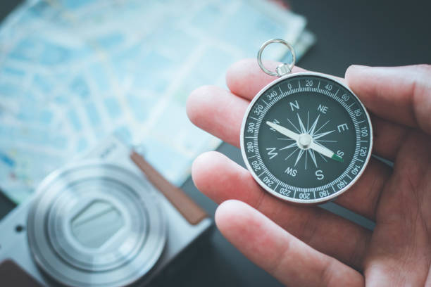 istock Young man on an adventure is holding a compass in his hand for finding is route 1179810725