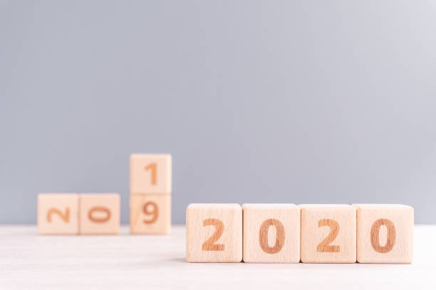 istock Abstract 2020, 2019 New year target plan design concept - wood blocks cubes on wooden table and pastel blue background, close up, blank copy space. 1179811099
