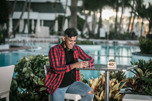 istock Cheerful ethnic male using smartphone while resting near pool 1179811190