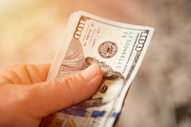 Unrecognizable mature man holding US one hundred Dollar bills. Horizontal shot.
