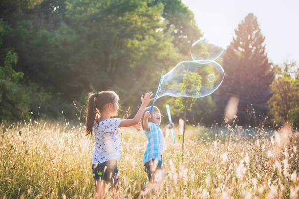 istock Little friends playing with soap bubbles 1179816080