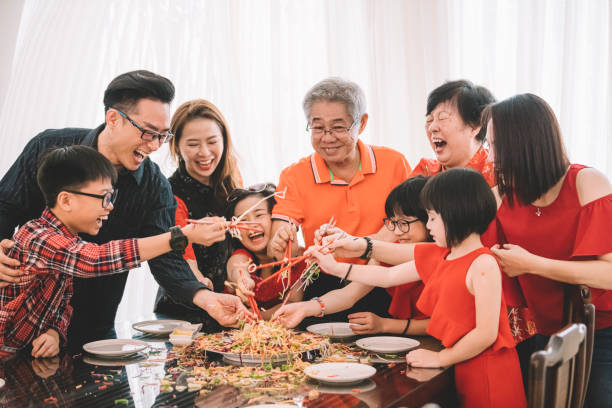 eine asiatische chinesische familie feiert chinesischen silvester mit traditionellen speisen lou sang (rohe fischgerichte) beim wiedersehen abendessen - chinesisches neujahr fotos stock-fotos und bilder