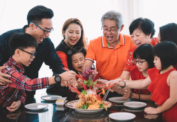 eine asiatische chinesische familie feiert chinesischen silvester mit traditionellen speisen lou sang (rohe fischgerichte) beim wiedersehen abendessen - chinesisches neujahr fotos stock-fotos und bilder