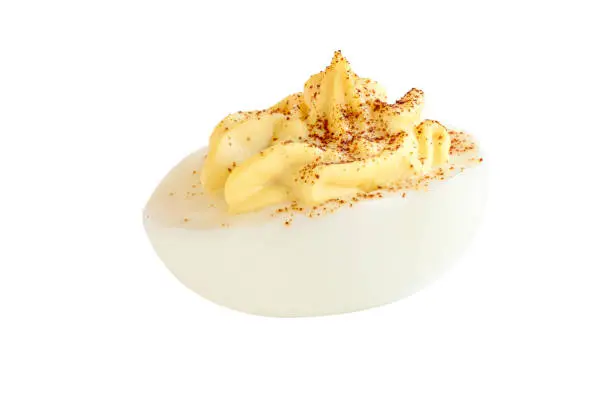 A deviled egg halves sprinkled with paprika and isolated over a white background. Clipping path included.