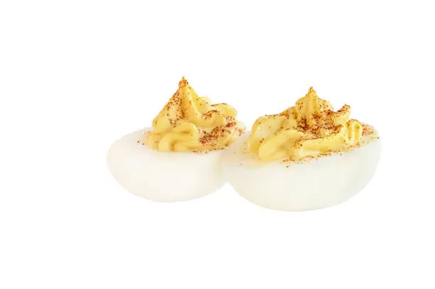 Two deviled egg halves sprinkled with paprika and isolated over a white background. Clipping path included.