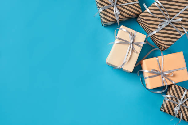 istock Different sizes, striped and plain paper gift boxes tied with ribbons and bows on a blue background. Close-up, copy space, top view 1179820064