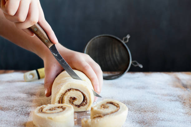 istock Woman Cutting Cinnamon Roll Slices 1179822170