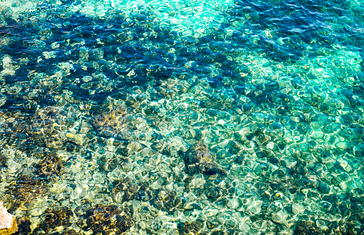 Sun glare on the blue water on the sea and on the bottom with stone, Blue Lagoon, Malta