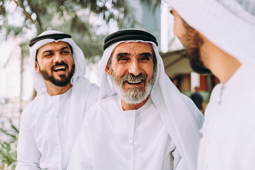 Tres hombres de negocios caminando en Dubái con ropa tradicional de emiratí photo