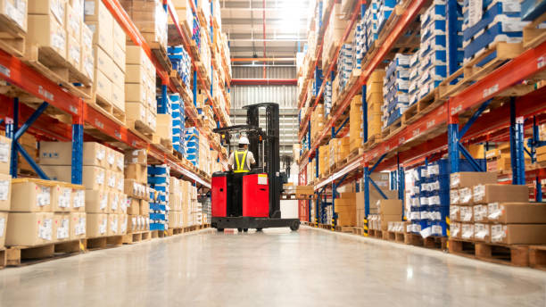 Warehouse Worker Worker in forklift-truck loading packed goods in huge distribution warehouse with high shelves. distribution warehouse stock pictures, royalty-free photos & images