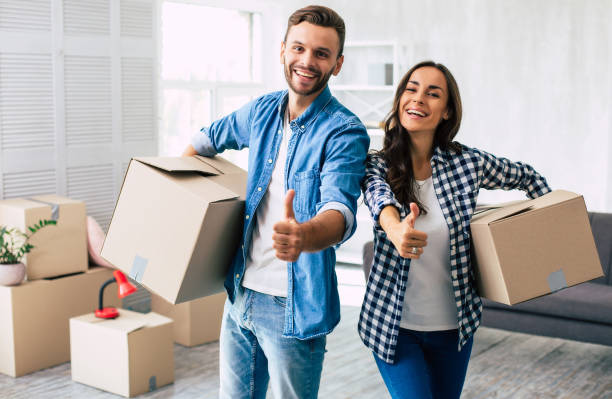 Thumbs up. A young family couple proves that everything is going great with their relocation by putting the thumbs up and smiling widely. stock photo