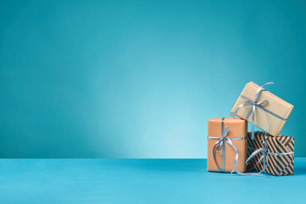 istock Different sizes, colorful, striped and plain paper gift boxes tied with ribbons and bows on a blue surface and background. Close-up, copy space 1179828421