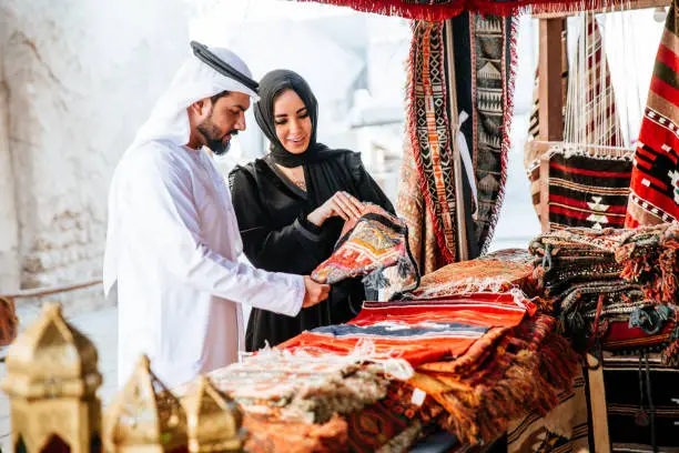 Happy couple spending time in Dubai. man and woman wearing traditional clothes making shopping in the old city