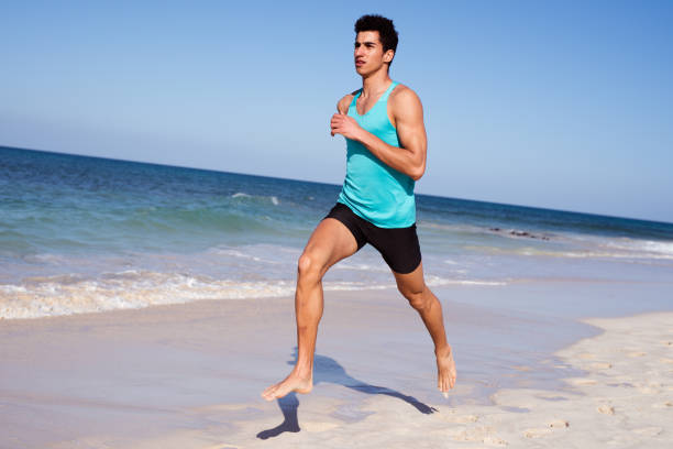 istock Young man sprinting on the beach in the sun 1179838998