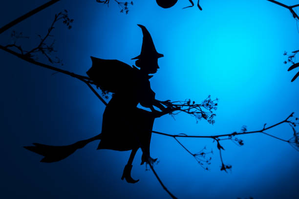 Creative trendy Halloween background with a flying witch silhouette a blue neon light background. Copy space. Halloween card and design concept, minimalism