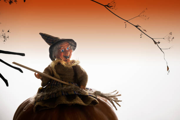 Witch sits on a pumpkin. Creative Halloween composition, card or poster. orange gradient light background. Halloween background and design concept, copy space