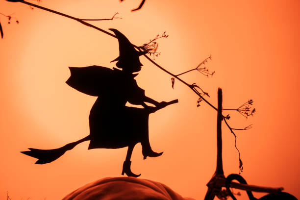 istock Witch flies on the Sabbath. Creative trendy Halloween background with a flying witch silhouette and spiders a orange gradient light background 1179839278
