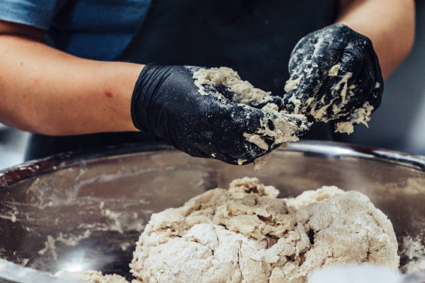 chef fêmea que prepara a massa de pão para o pão e os rissóis self feitos em luvas pretas - bread kneading making human hand - fotografias e filmes do acervo