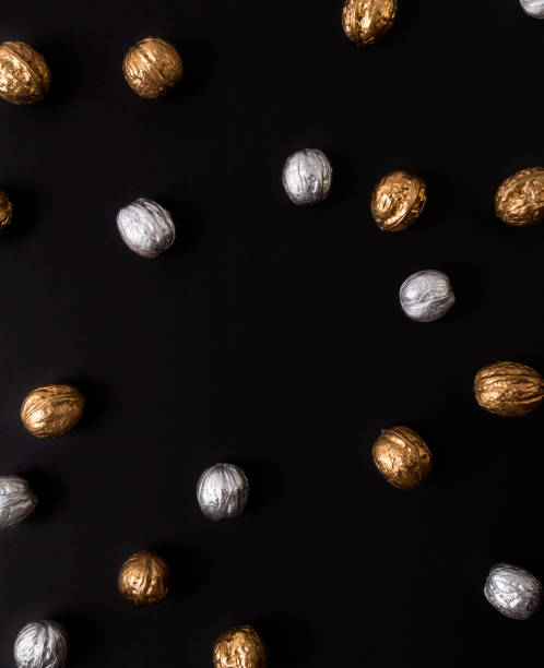 Painted golden and silver walnuts on black background.