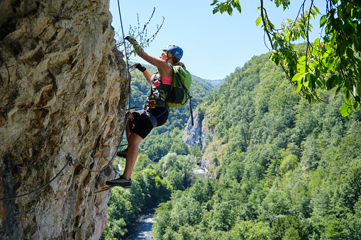 Woman on via ferrata at Suncuius, Bihor county, Romania, on a bright sunny day, with Crisul Repede defile below her.
