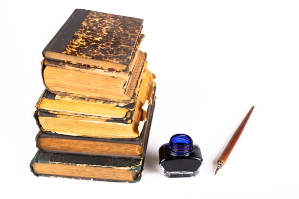 istock Old dusty books and writing nib on a bright countertop. Library items in old bindings. White background. 1179847709