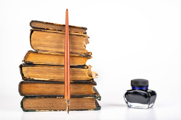 istock Old dusty books and writing nib on a bright countertop. Library items in old bindings. White background. 1179848344