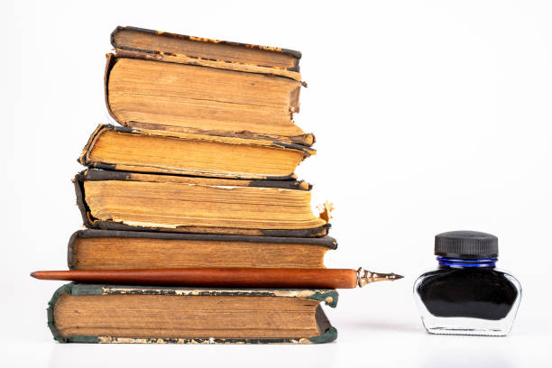 istock Old dusty books and writing nib on a bright countertop. Library items in old bindings. White background. 1179848433