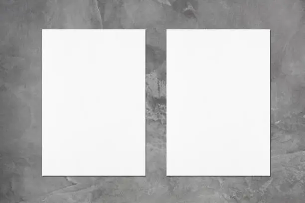 Photo of Two empty white vertical poster mockups on dark grey concrete background