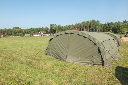large, green, military canvas tents pitched on a meadow
