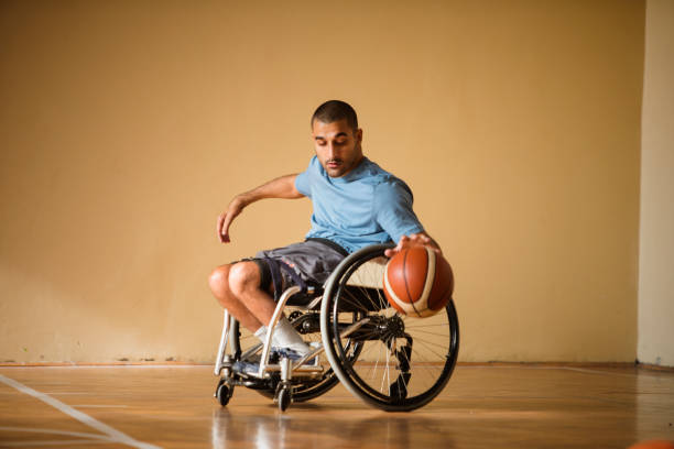l'homme handicapé joue au basket-ball de son fauteuil roulant - sports en fauteuil roulant photos et images de collection