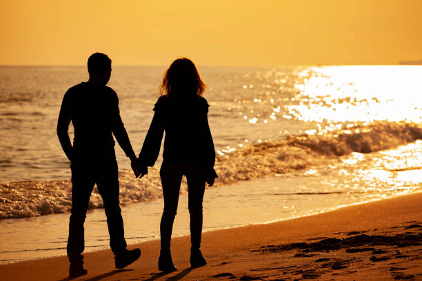 istock Young Couple Walking on Romantic Beach at Sunset 1179850287
