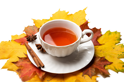 A cup of tea on yellow and red foliage isolated on a white background table. Autumn concept, top view