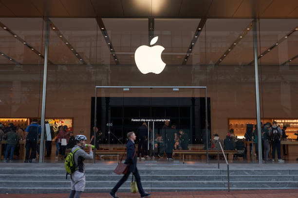 Apple Store in Downtown Portland Portland, Oregon, USA - Oct 1, 2019: A man strides past an Apple Store in downtown Portland. The big screen inside is seen advertising Apple's fastest A13 Bionic chips in the new iPhone series. apple computers photos stock pictures, royalty-free photos & images