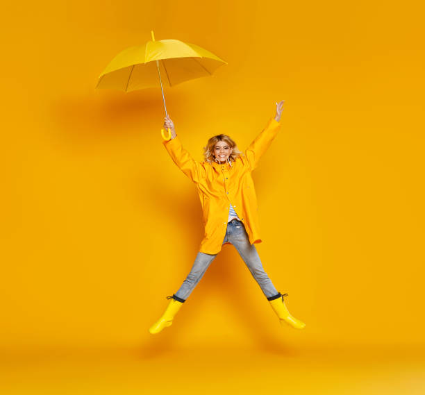 junge glückliche emotionale mädchen lachen mit regenschirm auf farbigen gelben hintergrund - 11998 stock-fotos und bilder