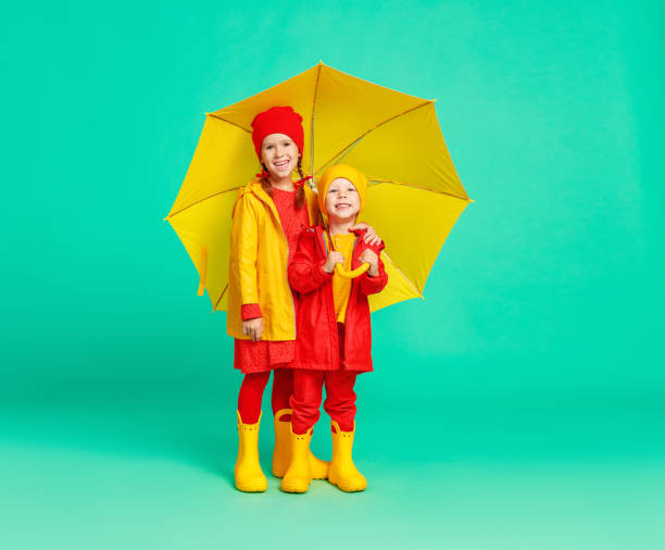 jóvenes felices y alegres amigos amigos riendo con paraguas amarillo sobre fondo verde de color - 11981 fotografías e imágenes de stock
