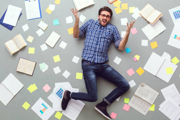 istock Young man isolated on grey background with papers and notes unsatisfied 1179885340