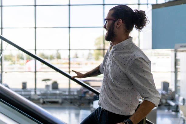 istock Young hipster person standing on escalator on airport 1179888812