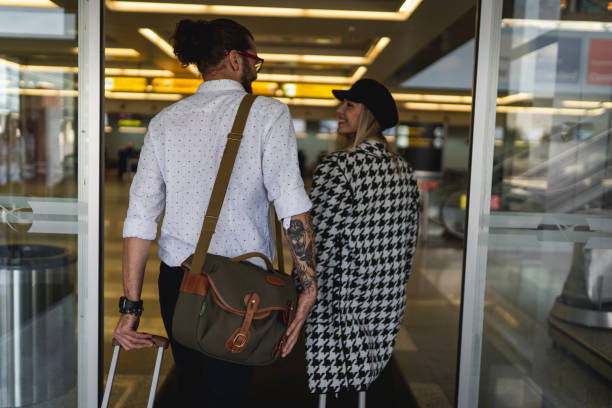 Young couple arriving at the airport Young couple arriving at the airport walking into glass door stock pictures, royalty-free photos & images