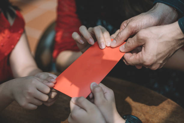 伝統として家族の子供たちにアンパオ、赤い封筒を与える人間の手を閉じる - hong bao ストックフォトと画像