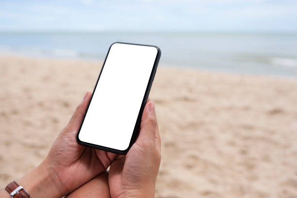 istock hands holding black mobile phone with blank desktop screen by the sea 1179891637