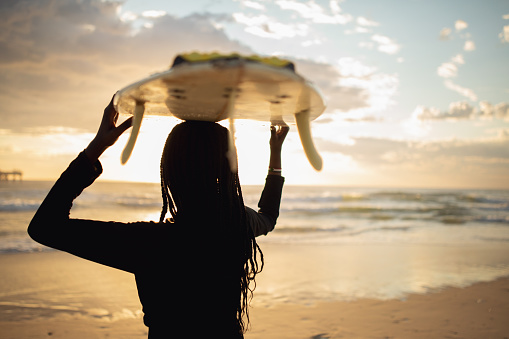 Portrait Of Young African Girl With Surfboard At Pristine Beach at Sunrise in Australia