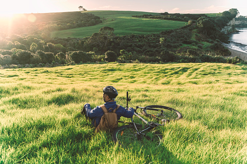 Professional road cyclist sit on the open field watch sunset