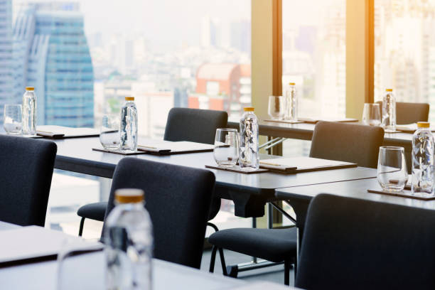 istock Plastic water bottles, Drinking glasses with pencil and white papers setup on the table prepared for seminar or business meeting in the hotel conference room 1179905685