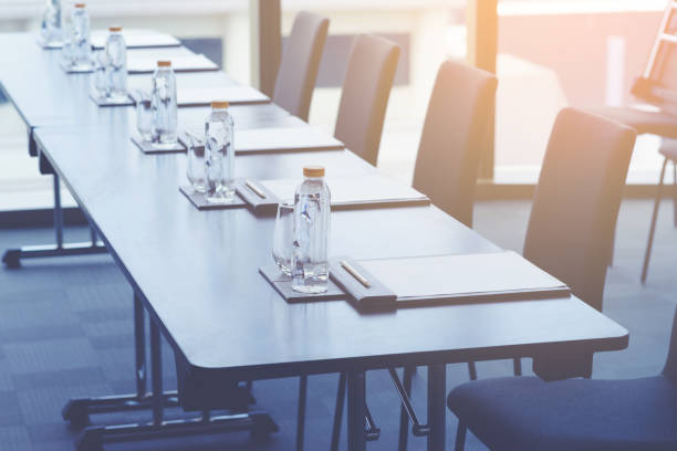 istock Plastic water bottles, Drinking glasses with pencil and white papers setup on the table prepared for seminar or business meeting in the hotel conference room 1179905721